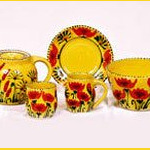 set of pottery kettle, mug, plate and bowl with yellow design and red flowers